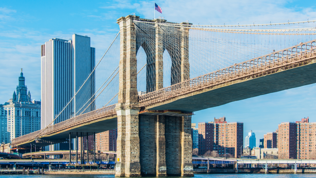 Panorama del ponte di Brooklyn al tramonto con lo skyline di Manhattan illuminato.