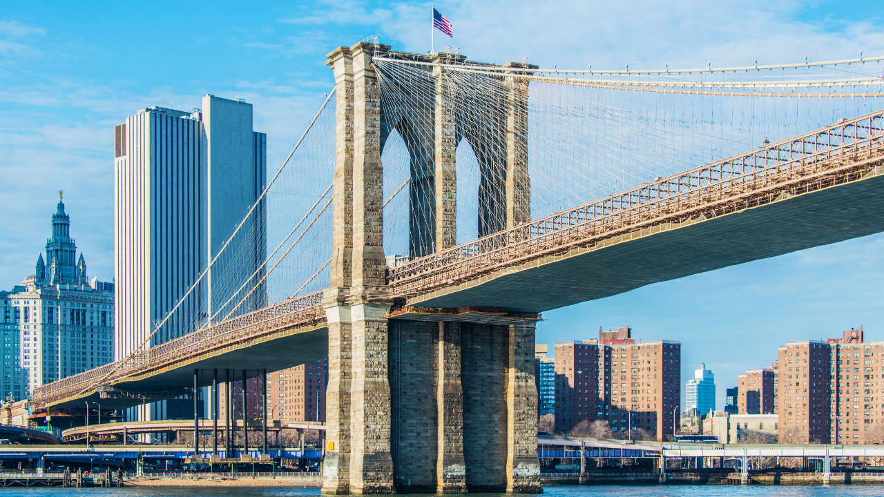Panorama del ponte di Brooklyn al tramonto con lo skyline di Manhattan illuminato.